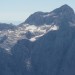 Zoomirana severna stena Triglava, sam vrh s Kredarico in desno spodaj planinska kavka